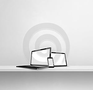 Laptop, mobile phone and digital tablet pc on white concrete wall shelf. Square background