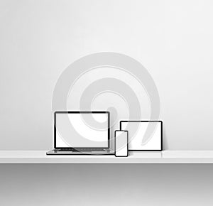 Laptop, mobile phone and digital tablet pc on white concrete wall shelf. Square background