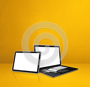 Laptop, mobile phone and digital tablet pc on yellow office desk
