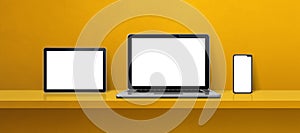 Laptop, mobile phone and digital tablet pc on yellow wall shelf. Banner background