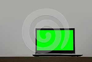 Laptop mock up with green blank mockup screen on wooden table isolated on white background. empty copy space. mock up laptop and
