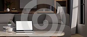 Laptop mockup and copy space on coffee table over blurred living room with couch in background