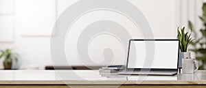 Laptop mockup and copy space on tabletop over blurred white living room in the background