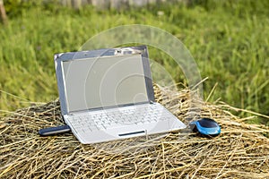 laptop with modem lies on a haystack in a meadow evening at sundown