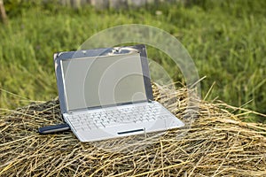 laptop with modem lies on a haystack in a meadow evening at sundown