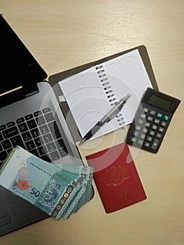 Laptop , money ,passport, pen,  calculator ,desk ,notebook with  blank pages