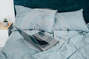 Laptop in the morning on a blue sheets bed. Work from home. Freelance Concept