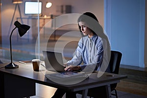 Laptop, night and business woman typing in office workplace working late on project. Computer, technology and female