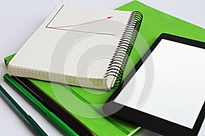 laptop and notebook are on a green weekly.Nearby are markers of green and black colors