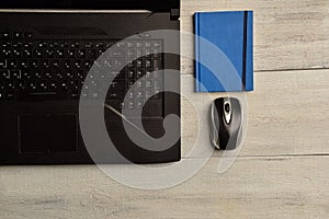 Laptop, notebook and mouse lie on a wooden table