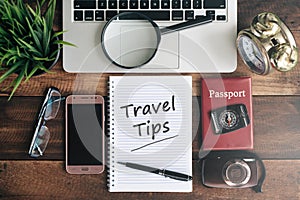 Laptop, notebook, smartphone, passport, compass, magnifying glass and clock with TRAVEL TIPS word photo