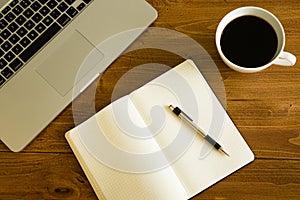 Laptop, notepad and coffee cup on wood table