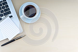 Laptop, notepad, fountain pen and cup of coffee on wooden background