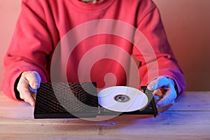 Laptop optical drive with compact disc in hands on table