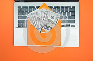 laptop and orange envelope with dollars