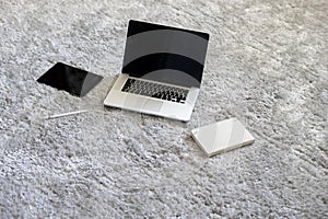 a laptop and other devices on the floor on the soft carpet in living room at home, isolation during coronavirus pandemy