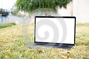 Laptop outside concept. Empty copy space, blank screen mockup. Soft focus laptop in nature background. Ecology travel