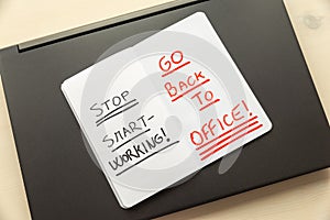 Laptop, and notebook with the words `stop smart working, go back to office`.