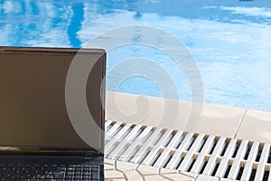 Laptop by the pool, work on holiday concept