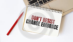 Laptop, red pen and notepad with text Dont resist change embrace in the white background