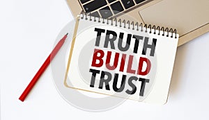 Laptop, red pen and notepad with text truth build trust in the white background