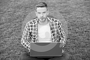 Laptop that is right to blog. Young blogger use laptop on green grass. Handsome man with laptop computer outdoors