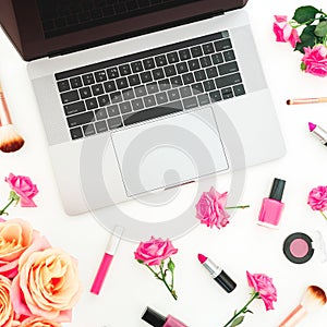 Laptop, roses flowers, cosmetics and accessories on white background. Flat lay. Top view. Beauty blogger composition