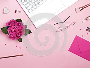 Laptop, roses, small papr hearts and other accessories on the pink background, top view