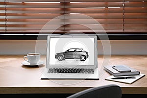 Laptop screen with automobile on table. Car buying