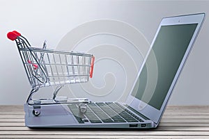 Laptop and shopping cart on wooden table