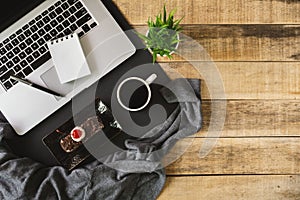 Laptop, small notebook and breakfast on wood background.