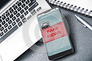 Laptop and smartphone with fake news alert