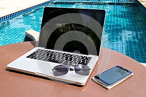 Laptop and smartphone near the pool