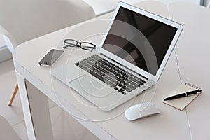 Laptop with smartphone and note book on table