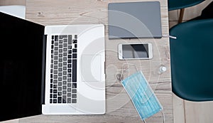 Laptop, smartphone and protective mask on the office Desk
