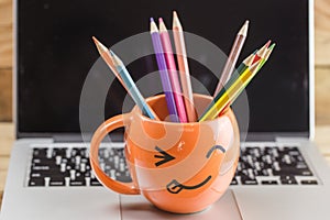 Laptop with smiley wrinkle happy face mug.