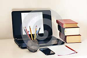Laptop, stack of books, notebook, smartphone in office background for education learning concept