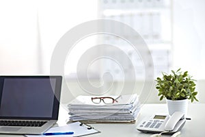 Laptop with stack of folders on table white background