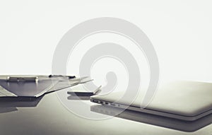 Laptop with stack of folders on table on white background