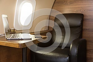 Laptop on the table in the interior of a private jet. Flying first class.