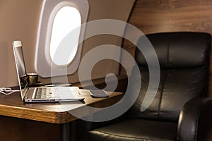 Laptop on the table in the interior of a private jet. Flying first class.