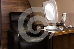 Laptop on the table in the interior of a private jet. Flying first class.