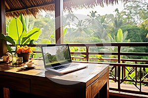 Laptop on the table of an open veranda overlooking the tropics. Minimalistic freelance home office
