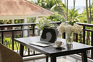 Laptop on the table of an open veranda overlooking the tropics. Minimalistic freelance home office