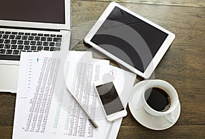 Laptop, tablet ,smartphone with financial documents on wooden table