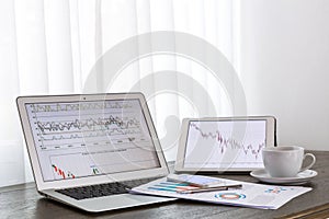 Laptop, tablet ,smartphone with financial documents on wooden table