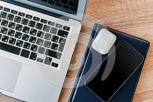 Laptop, tetra phone and bluetooth headphones on a wooden office desk