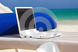 Laptop and towel on the beach chaise longue photo