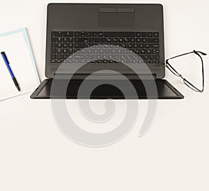 Laptop on the white background isolated.Glasses and notebook next to the laptop