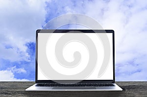 Laptop with white blank screen on wooden table and blue sky back